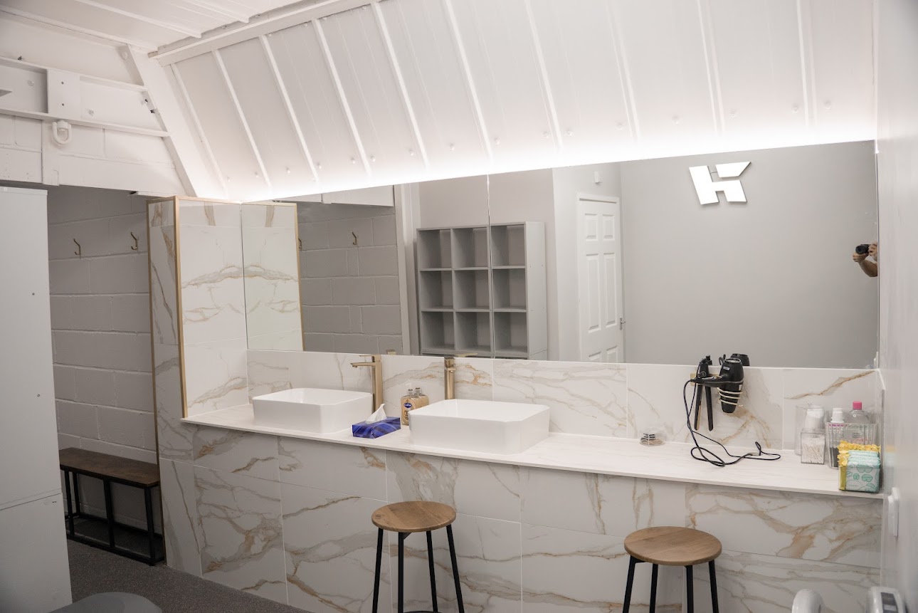 Modern changing rooms with marble-effect tiles, vanity area with stools